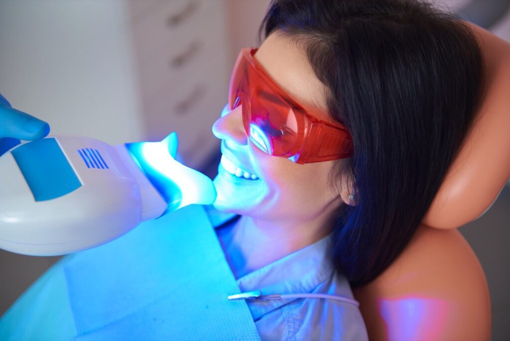 Woman having teeth whitened in dental office